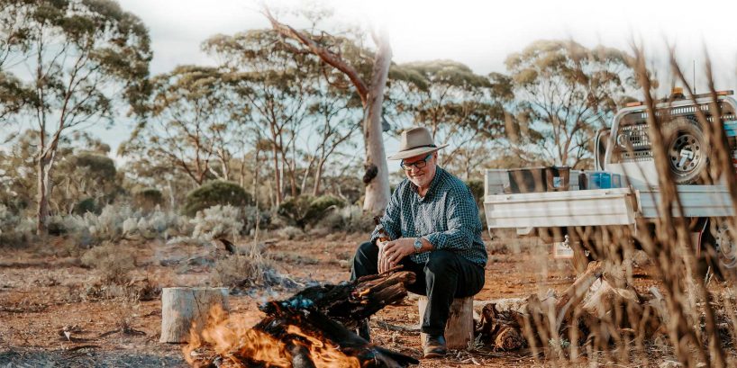 Max sitting at a campfire in the bush